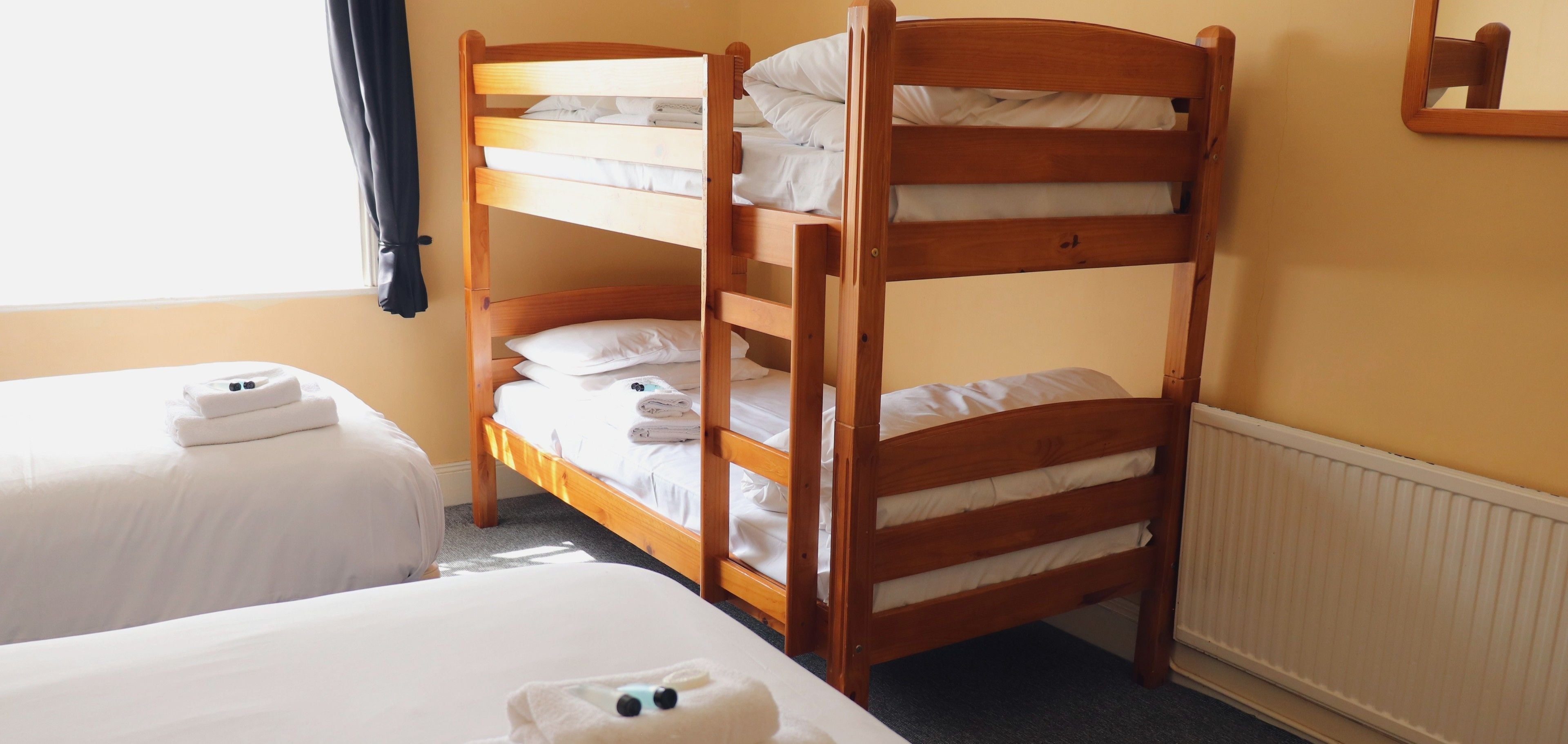 Habitación con literas, dos camas individuales y una litera de madera.