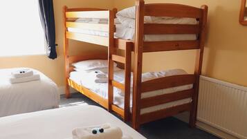 Habitación con literas, dos camas individuales y una litera de madera.