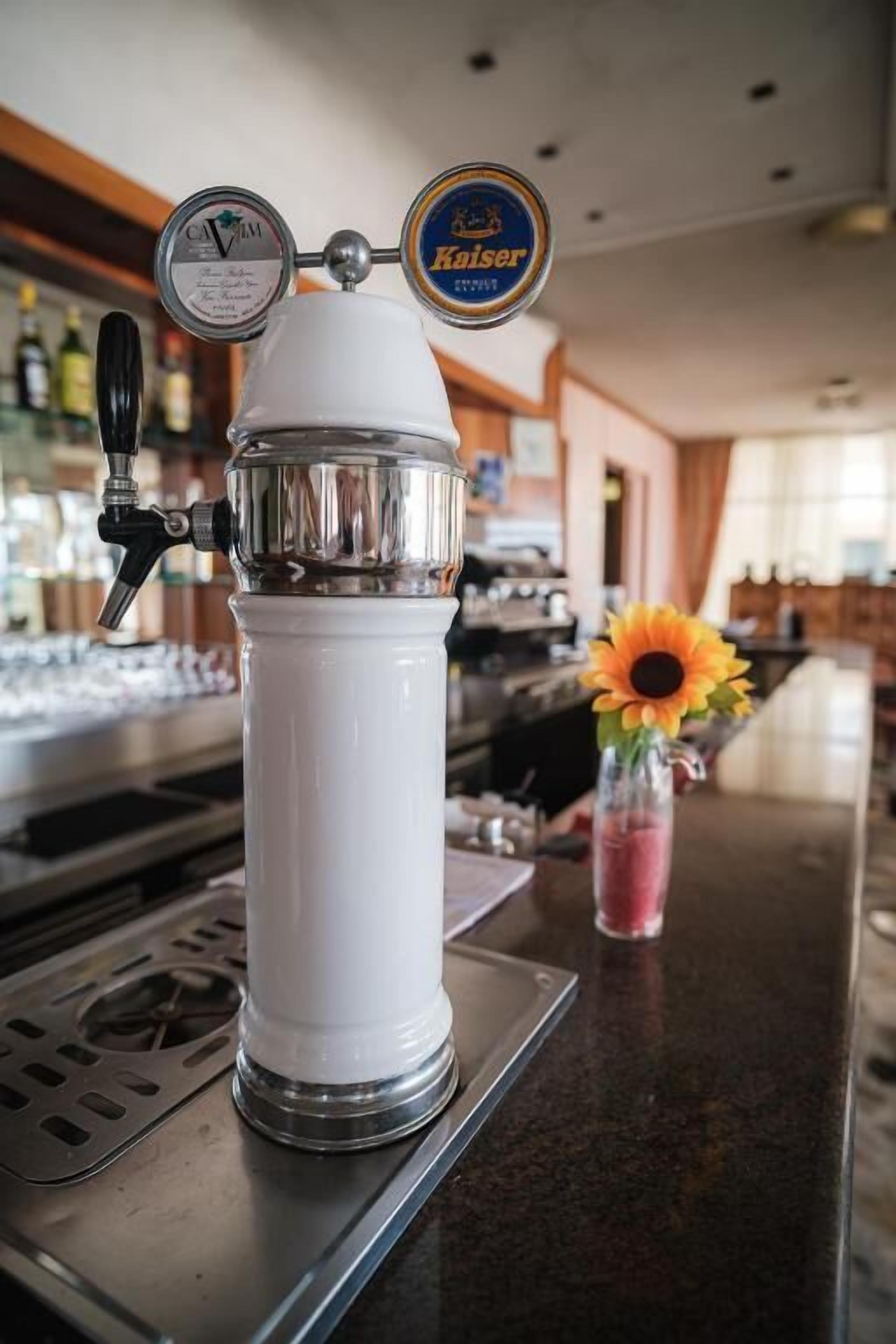 A bar with a beer tap, a beer keg, and a vase with a sunflower.