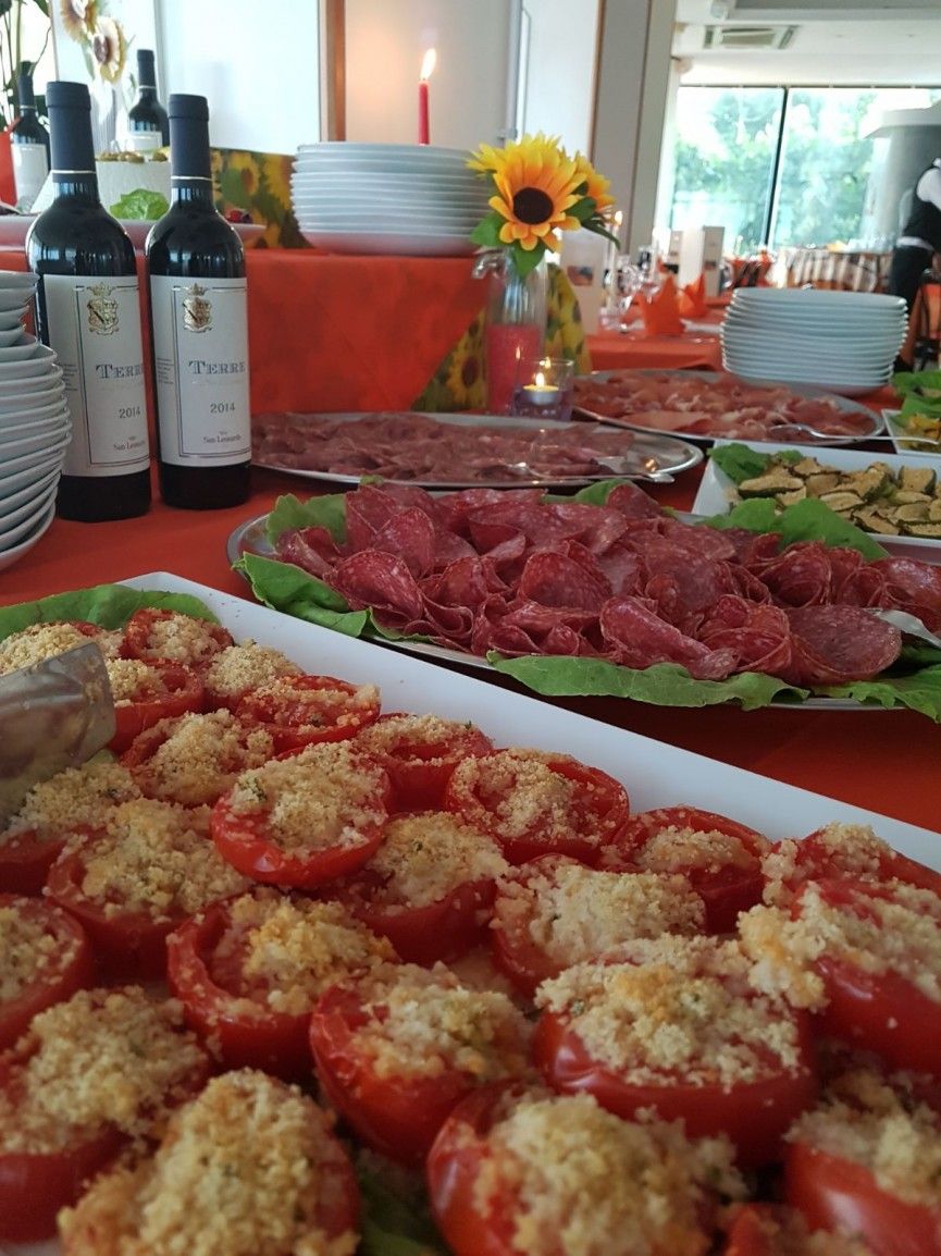 A table with food items, including stuffed tomatoes and meat slices, and wine bottles.