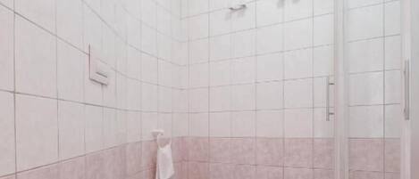 A bathroom with a toilet, a shower, and a tiled floor.