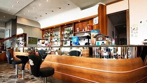 A bar area with wooden counter, bar stools, and shelves stocked with bottles.