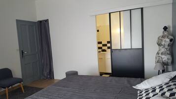Un dormitorio con una cama, una silla, un armario y un baño visible a través de una puerta abierta.