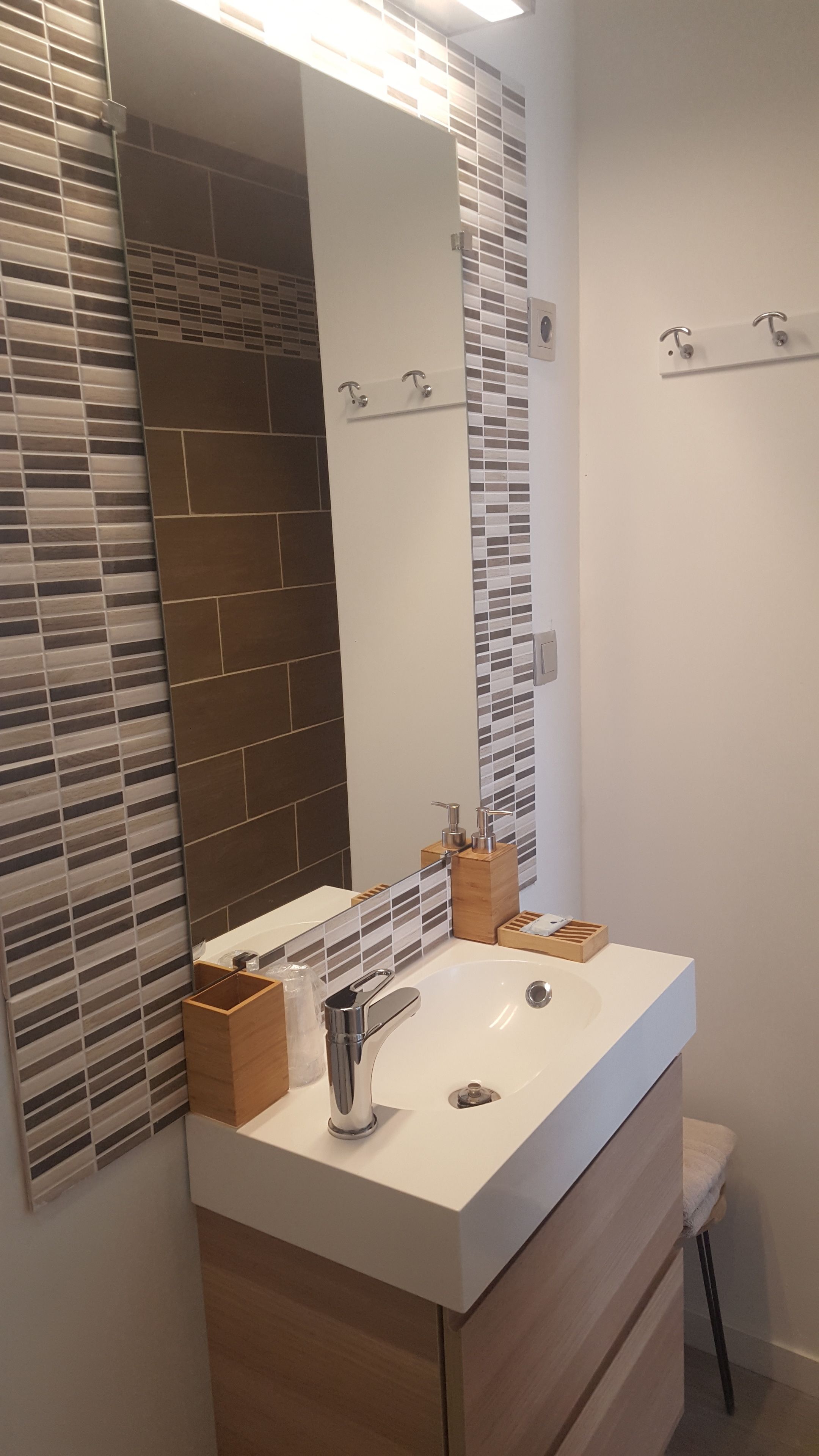 Une salle de bain moderne avec un lavabo blanc, un meuble-lavabo en bois et un grand miroir.