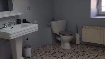 Une salle de bain avec un lavabo, des toilettes et un radiateur. Le sol est recouvert de carreaux décorés.
