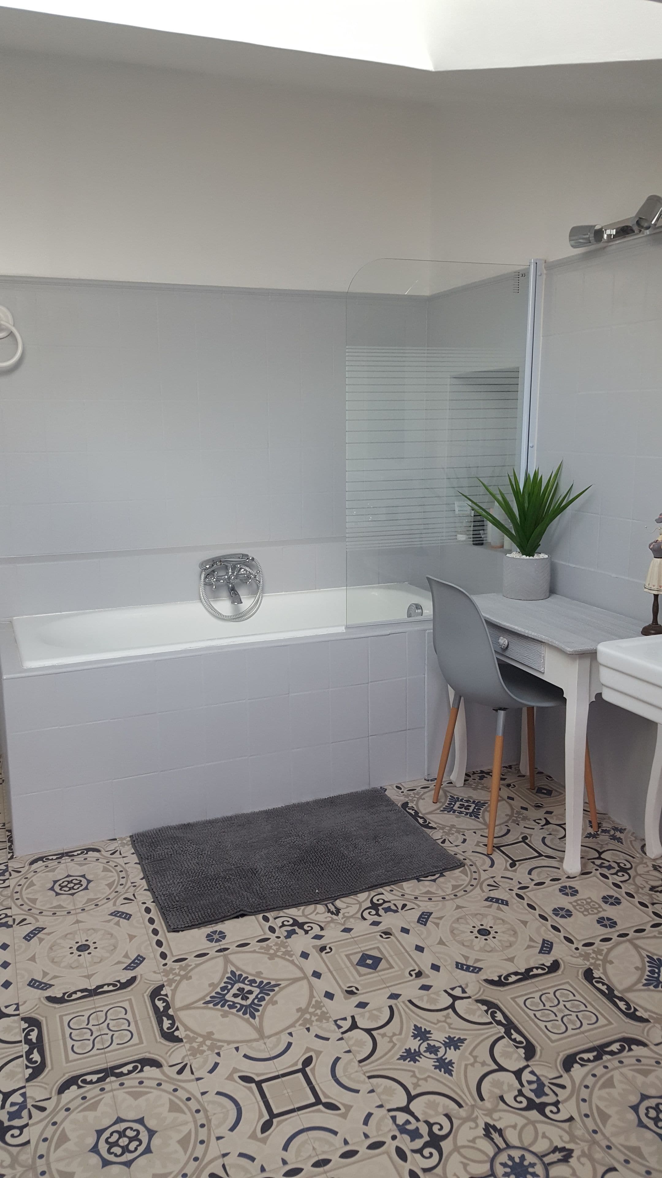 A bathroom with a bathtub, a sink, a chair, and a potted plant.