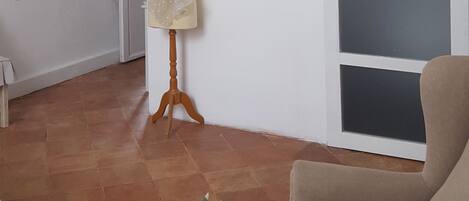 Una sala de estar con un maniquí sobre un soporte, un sillón color beige, un tapete estampado y una planta en maceta sobre una mesa redonda.