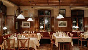 A restaurant with wooden paneled walls, multiple tables and booths, and hanging pendant lights. - Fränkischer  Gasthof  Hotel Zum Koppen (Gemuenden)