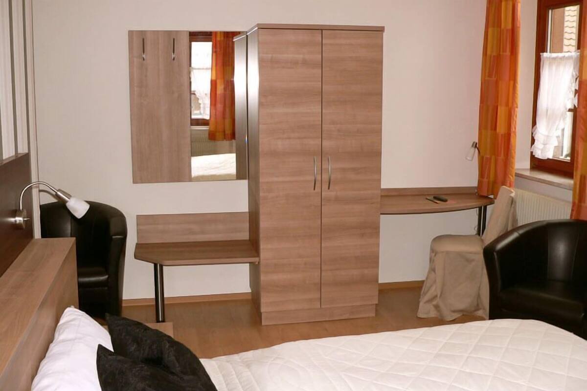 Une chambre d’hôtel comprenant un lit, un bureau, une armoire, une chaise et un miroir.