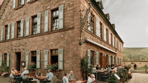 A stone building with multiple windows and outdoor seating areas. - Fränkischer  Gasthof  Hotel Zum Koppen (Gemuenden)
