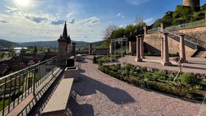 A historical site with a castle tower, a bridge, and a paved walkway with benches. - Fränkischer  Gasthof  Hotel Zum Koppen (Gemuenden)