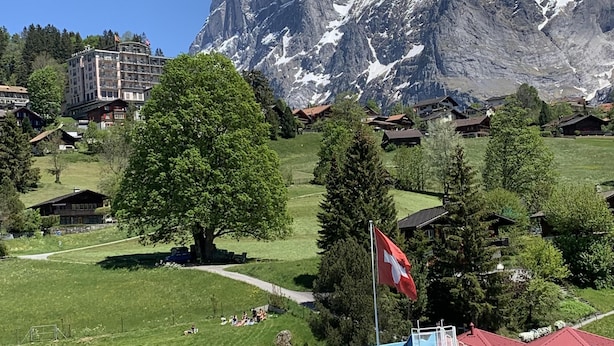 A hotel with a pool, red-roofed buildings, and a mountain backdrop.
