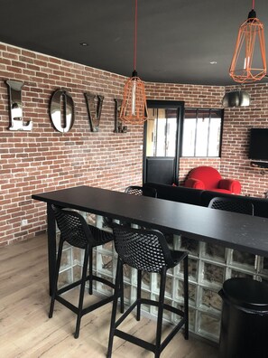 Eine moderne Küche mit Backsteinwand, einer schwarzen Arbeitsplatte und zwei schwarzen Barhocker.