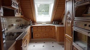 A kitchen with wooden cabinets, a built-in oven, and a window with a view of greenery.