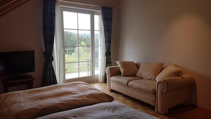 A bedroom with a large window, a sofa, and a TV.