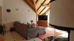 A living room with a sofa, a TV, and a large round table.