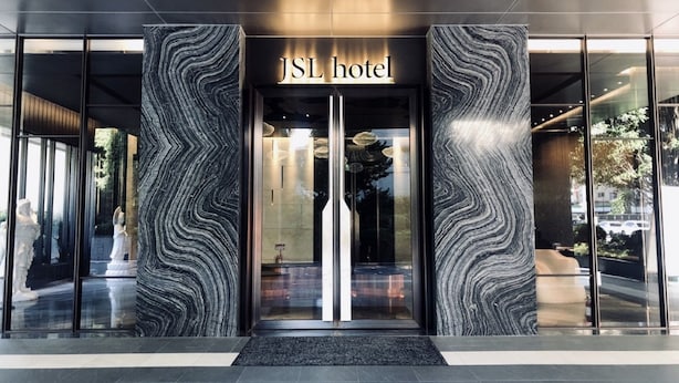 The entrance of JSL Hotel with a modern design, featuring a marble facade and a glass door entrance. - JSL Hotel (Taipei)
