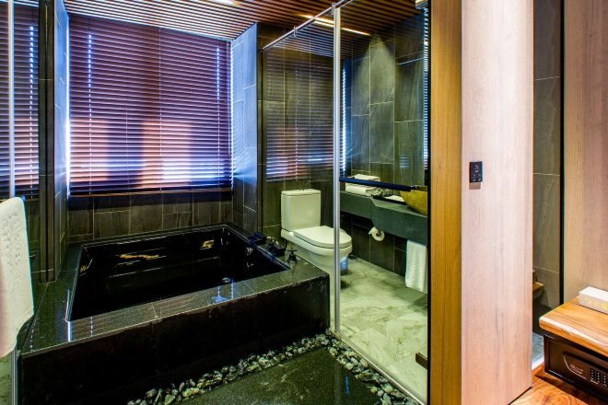 A modern bathroom with a black bathtub, a toilet, and a glass shower enclosure.