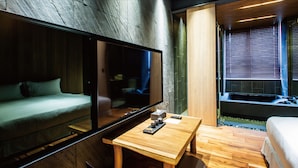 A modern bedroom with a large bed, a wooden table, and a TV mounted on the wall. - JSL Hotel (Taipei)
