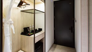 A hotel room with a wooden vanity, a black door, and a robe hanging on a rack. - JSL Hotel (Taipei)