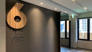 A modern hallway with a large wooden number 6 sign, a glass door, and a view of buildings outside. - JSL Hotel (Taipei)