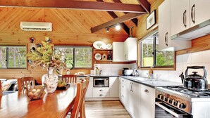 Une cuisine moderne avec des meubles blancs, une table à manger en bois et une grande fenêtre.