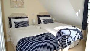 A bedroom with two beds, each with a headboard, white bedding, and striped blankets. - Pwll-y-Faedda (Builth Wells)