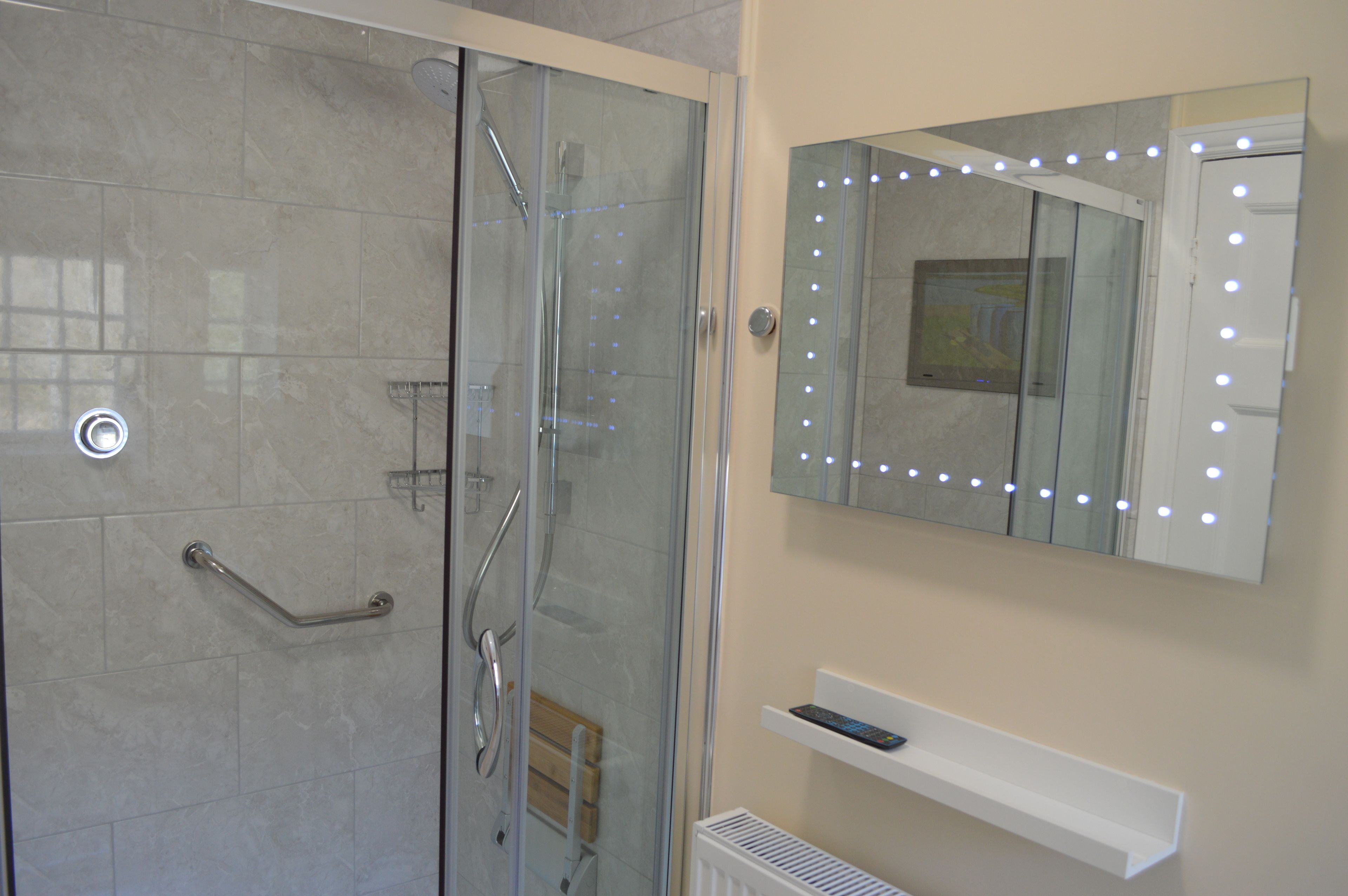 Une salle de bain avec une douche à parois de verre, un meuble-lavabo avec un miroir et une étagère.