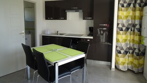 Une cuisine compacte avec un coin repas, comprenant une table avec des chaises, une machine à café et un réfrigérateur.