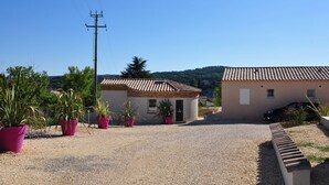 Un quartier résidentiel comprenant deux maisons, une allée gravillonnée et des plantes en pot.