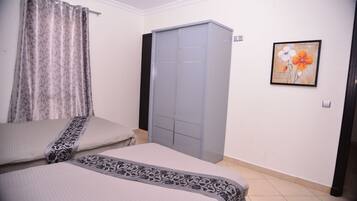 A bedroom with two beds, a wardrobe, and a framed picture on the wall.