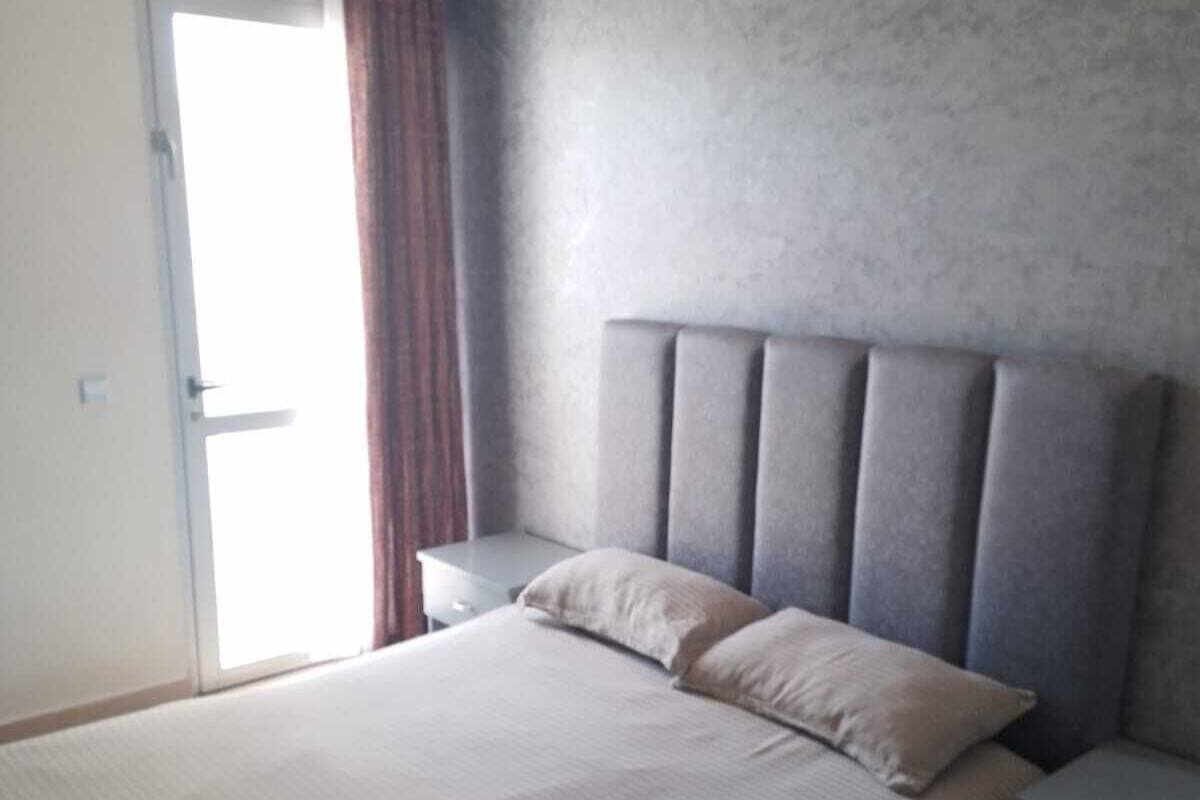 Een slaapkamer met een bed, een nachtkastje, een airconditioning en een schuifdeur.