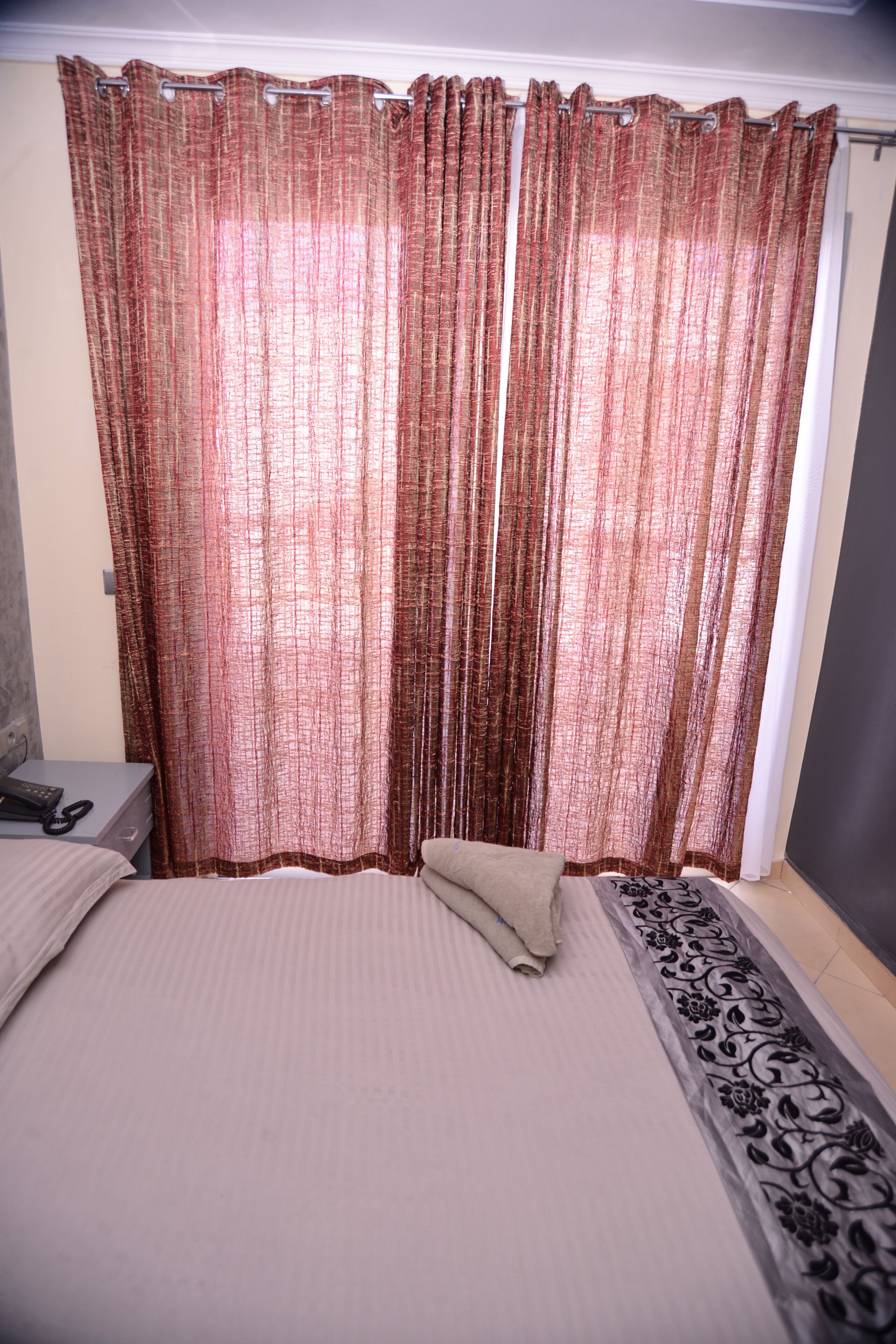 A bedroom with a bed, a bedside table, and a curtain.