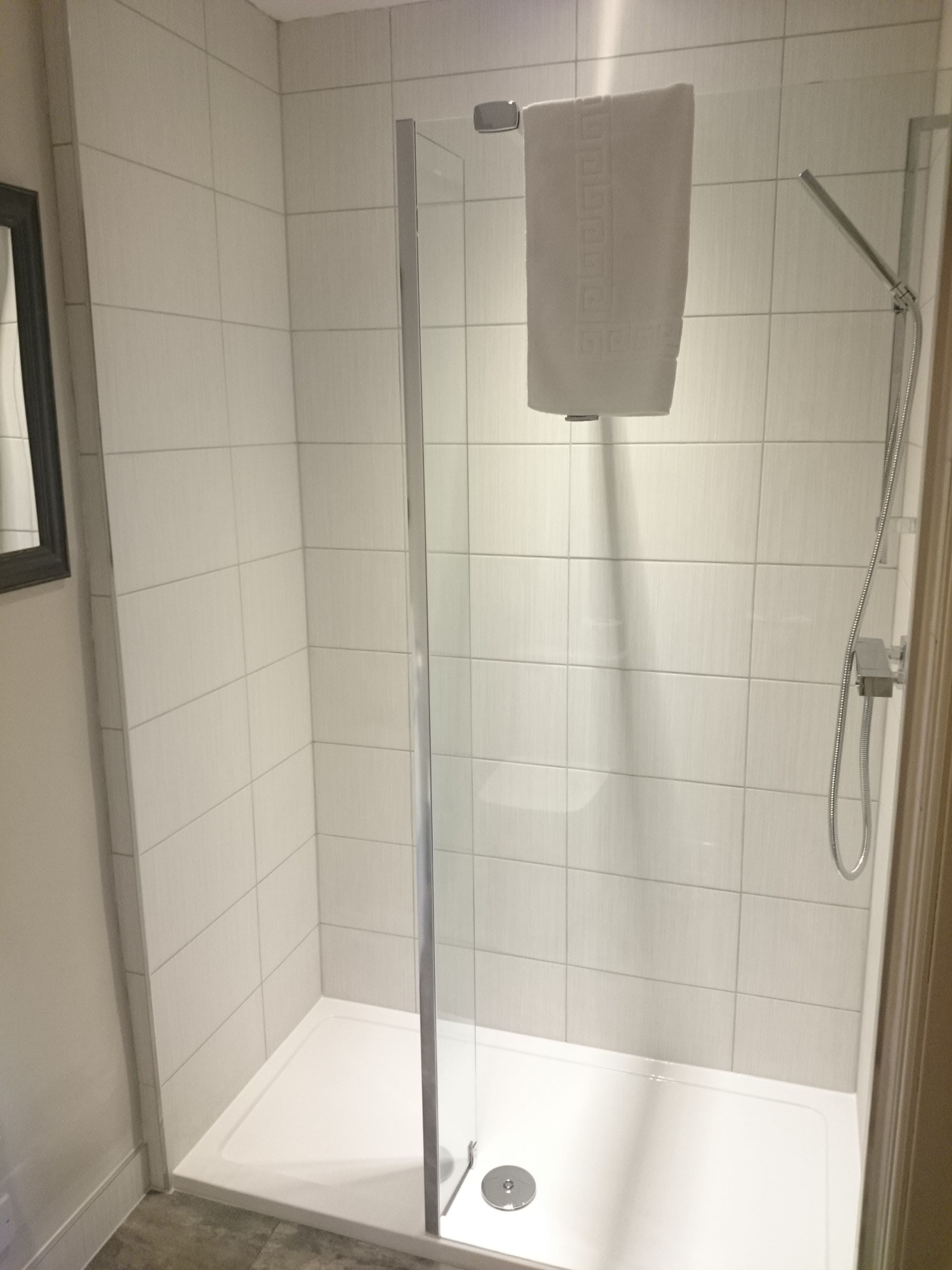 A glass-enclosed shower with a white towel hanging on the door.