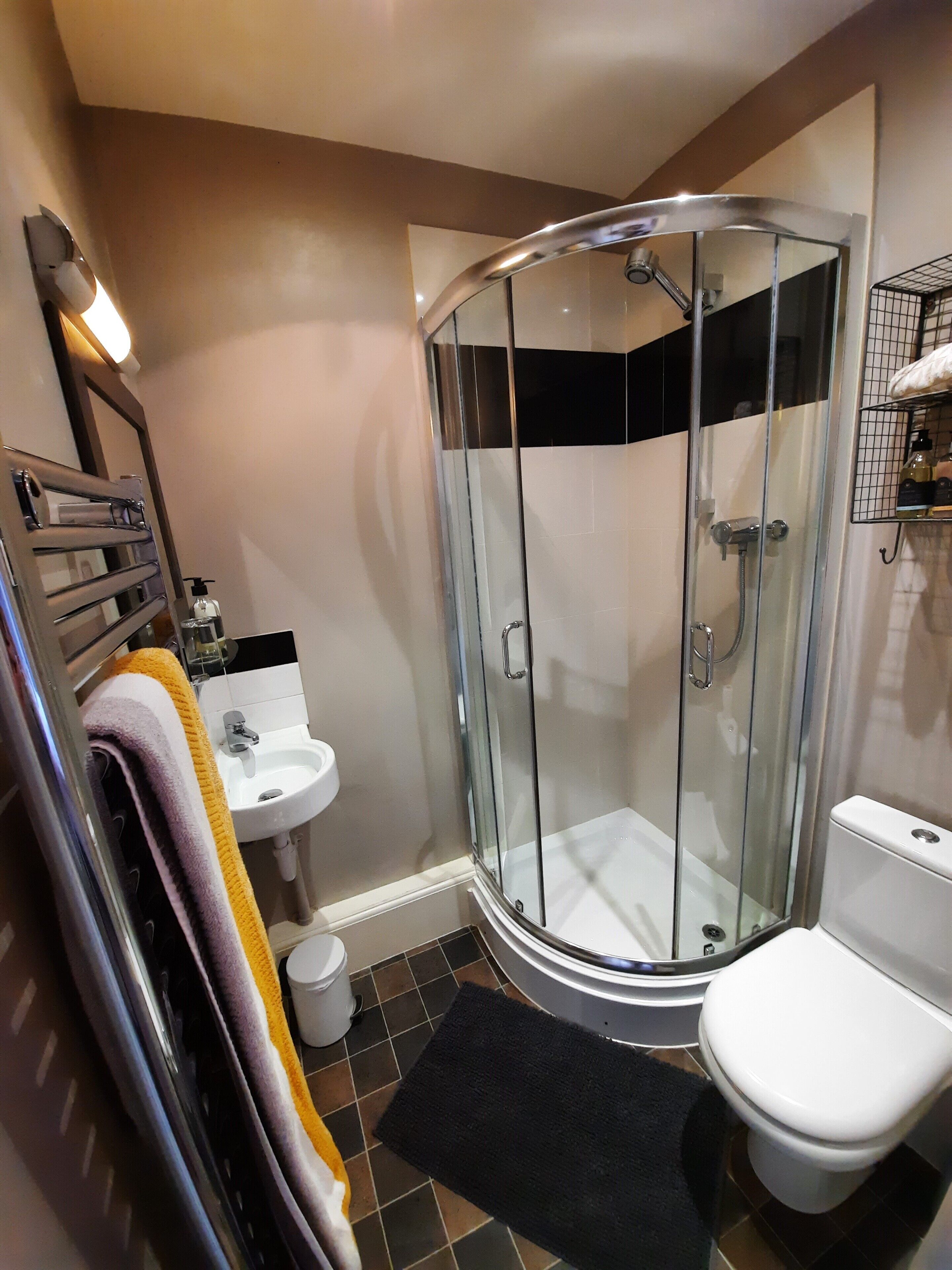 A modern bathroom with a glass-enclosed shower, a white sink, and a toilet.