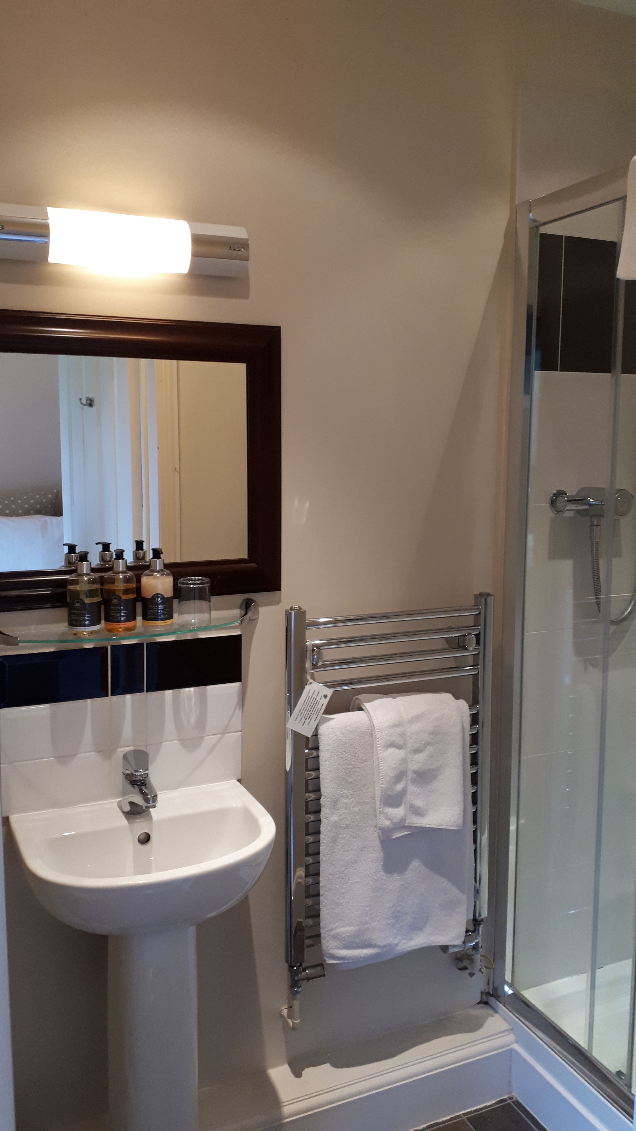 Un baño con lavamanos blanco, un espejo y una cabina de ducha de vidrio.