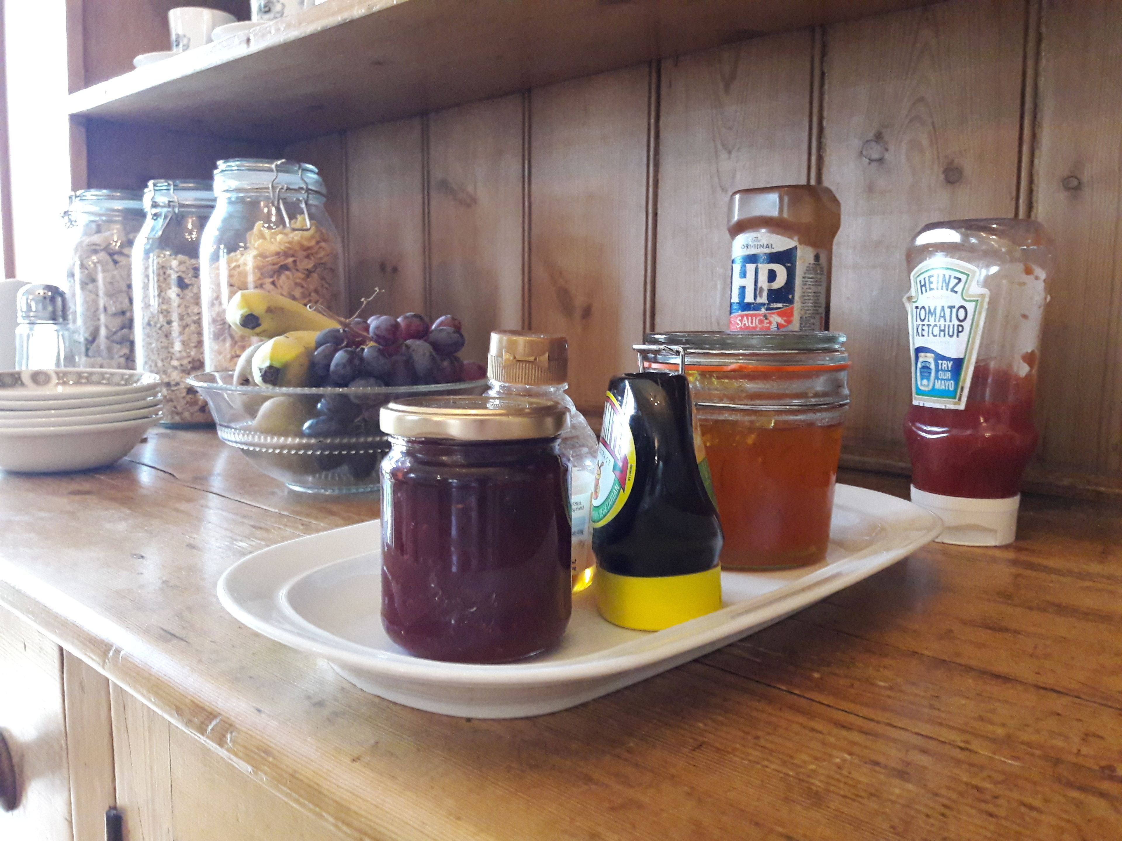 Un plan de travail de cuisine avec divers condiments et un bol de raisins.