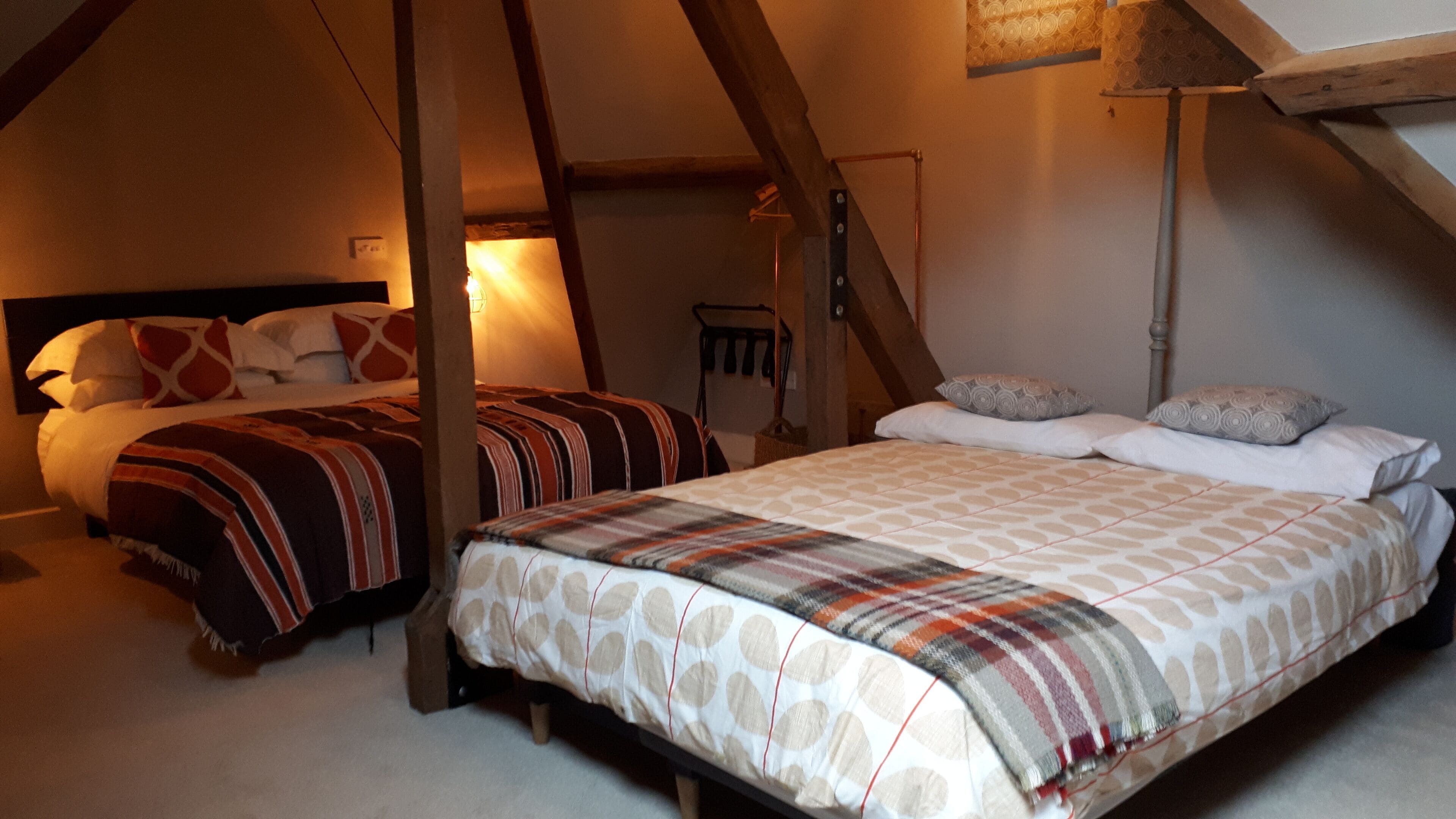 A bedroom with two beds, one with a striped bedspread and the other with a patterned bedspread.