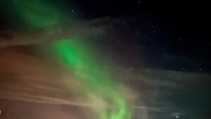 Una terraza de madera con jacuzzis y vistas de las auroras boreales.