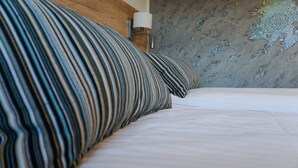Una cama bien hecha con almohadas a rayas y una pared con un motivo decorativo.