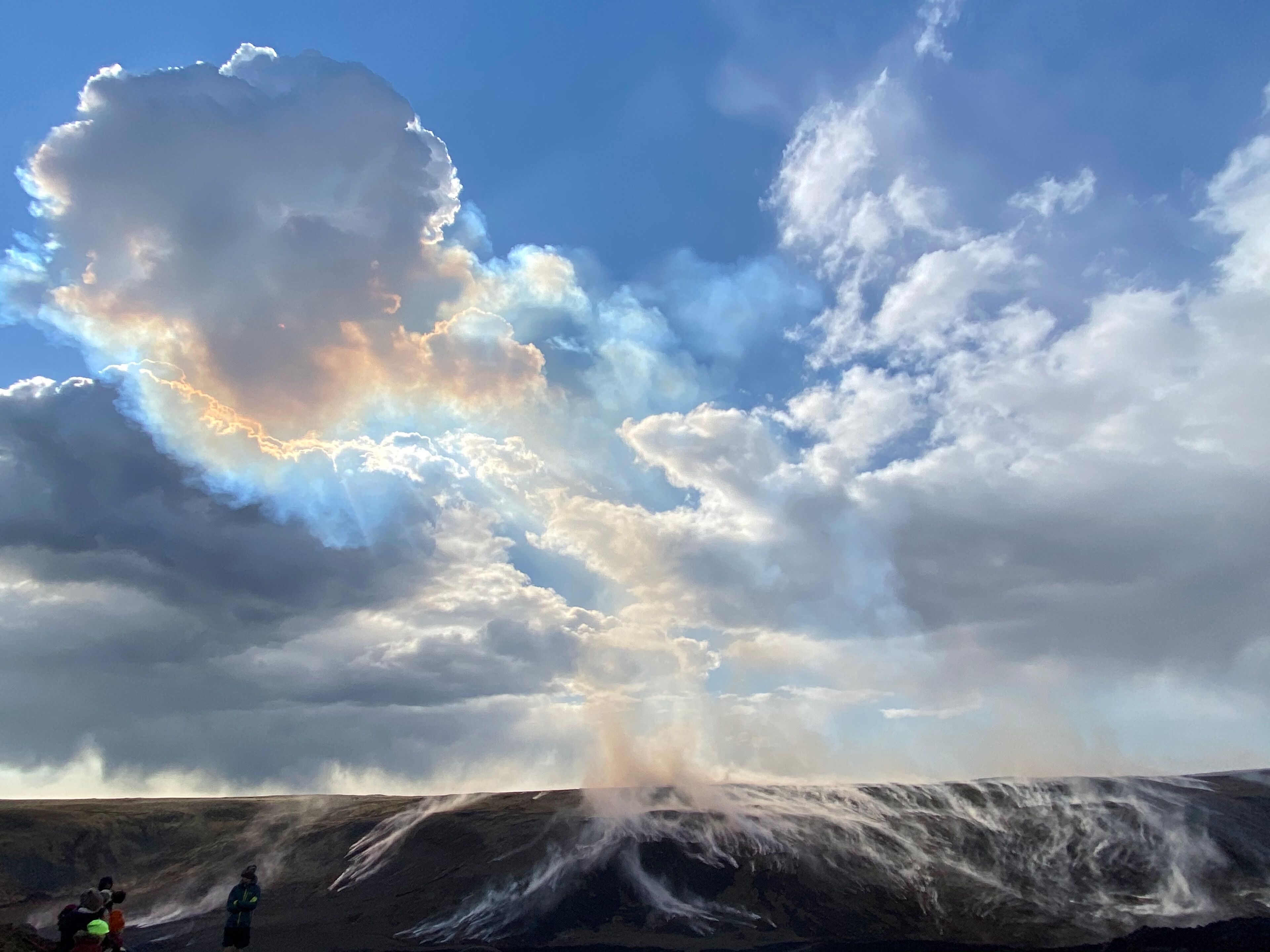 A landscape with a large cloud formation and a waterfall.