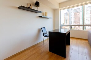 Una habitación moderna con una mesa negra, una silla negra y dos estantes flotantes decorados con objetos.