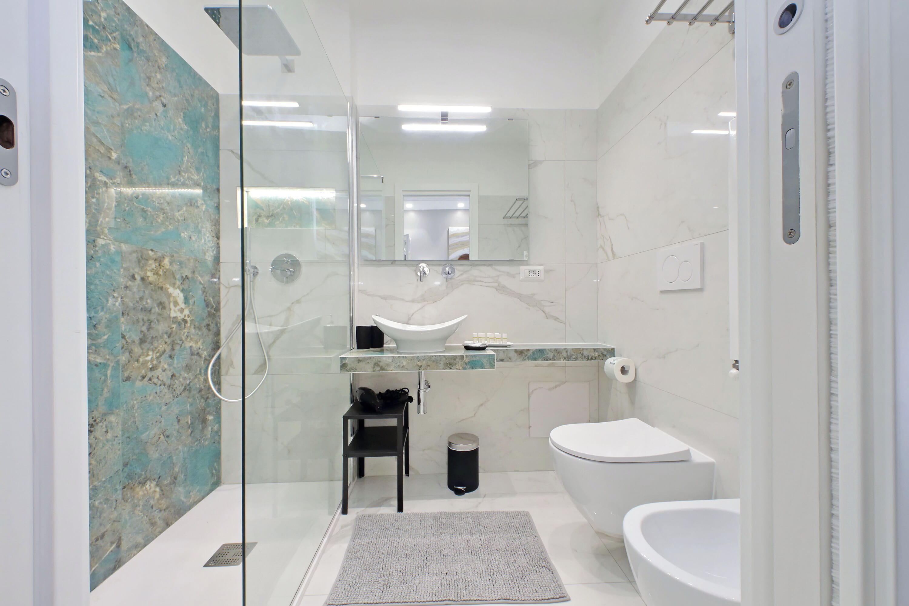 Ein modernes Badezimmer mit einer Duschkabine aus Glas, einem weißen Waschbecken und einer Toilette.