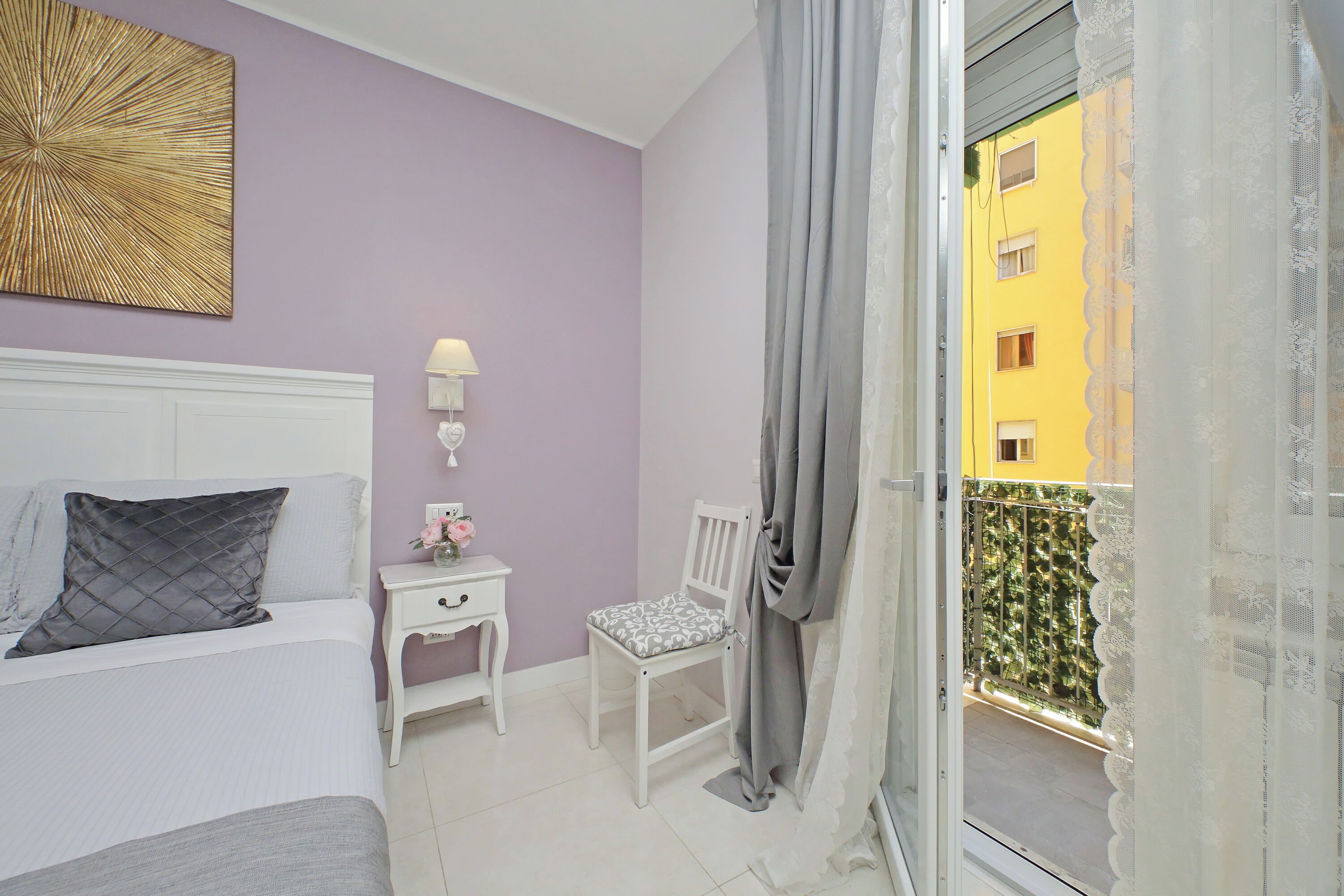 A bedroom with a bed, a nightstand, a chair, and a window with curtains.