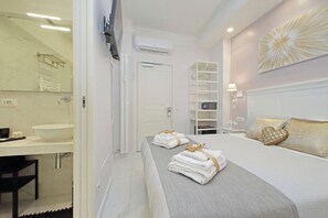 Een moderne hotelkamer met een groot bed, een badkamer met een wastafel en spiegel, en een inloopkast.