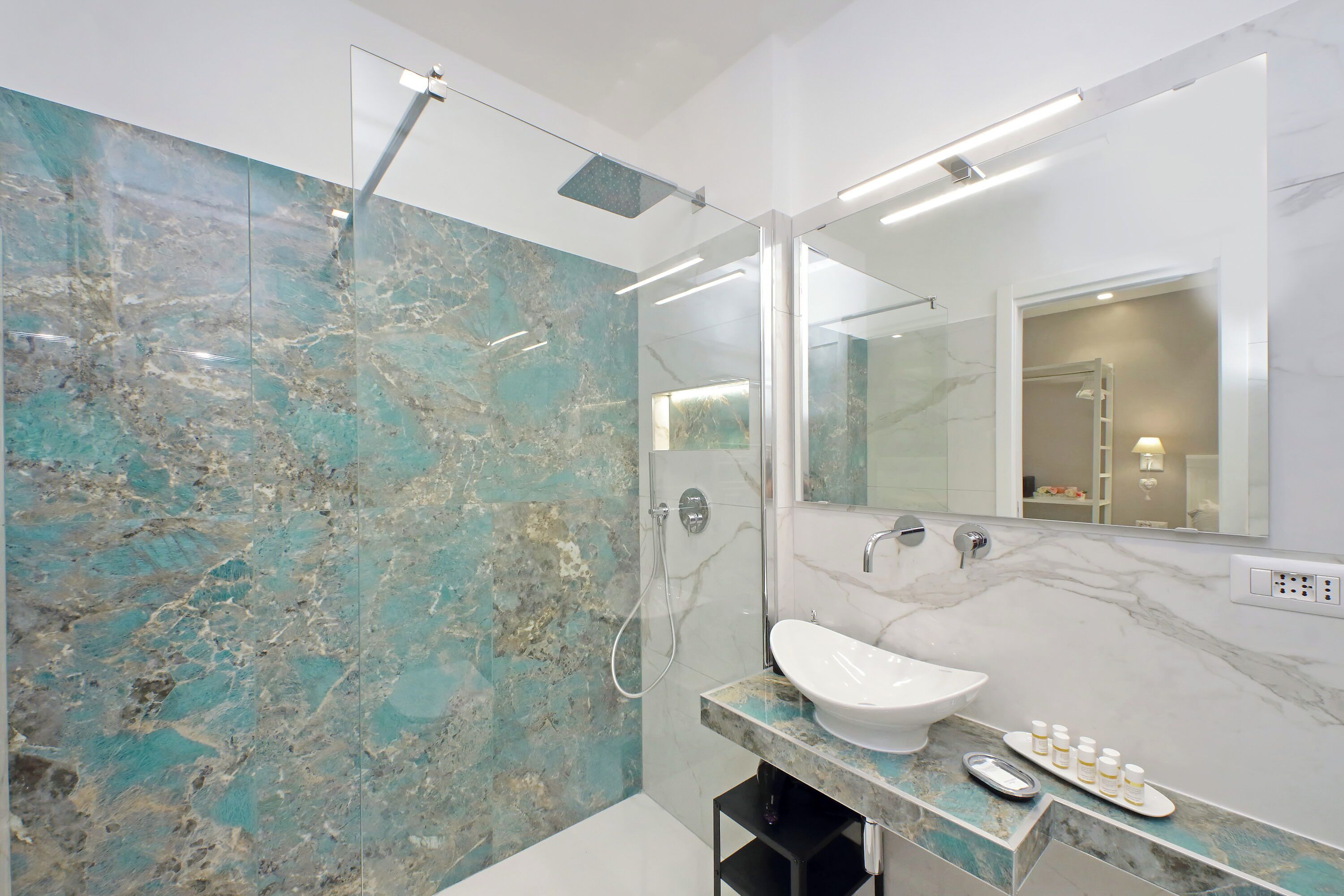 A modern bathroom with a marble vanity, a glass shower enclosure, and a large mirror.