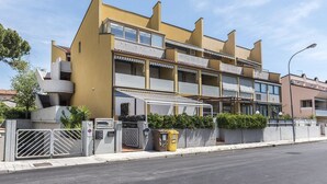 A multi-story building with balconies, a gated entrance, and a trash bin. - M053 - Marcelli, two-room apartment with garden 100 meters from the sea (Marcelli)