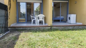 A small outdoor patio with a table and chairs, a washing machine, and a sliding glass door leading to a bedroom. - M053 - Marcelli, two-room apartment with garden 100 meters from the sea (Marcelli)
