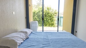 A room with a bed, a window, and a view of greenery outside. - M053 - Marcelli, two-room apartment with garden 100 meters from the sea (Marcelli)