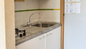 A kitchen with a stainless steel sink, a gas stove, and white cabinets. - M053 - Marcelli, two-room apartment with garden 100 meters from the sea (Marcelli)